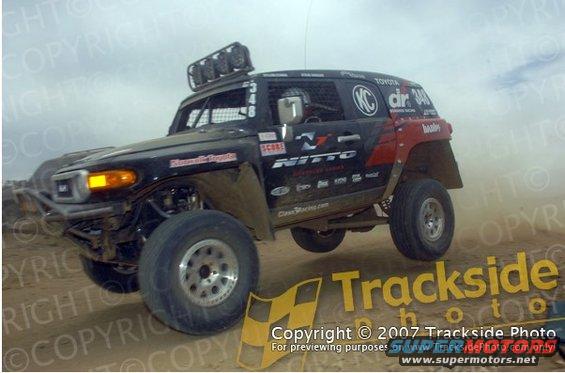 Black Toyota FJ Cruiser off-road racer with "Nitto" and "KC" logos, front 3/4 view