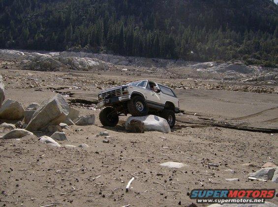 White Ford Bronco with lifted suspension navigating large rocks off-road