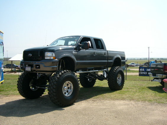 Dark gray lifted Ford F-250 Super Duty pickup truck with oversized tires, viewed from the front three-quarter angle