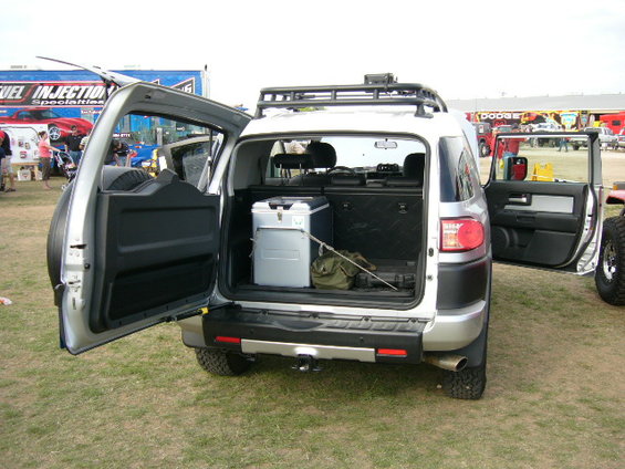 Toyota FJ Cruiser with rear doors open, showing cooler and gear in cargo area. Another vehicle is partially visible to the right