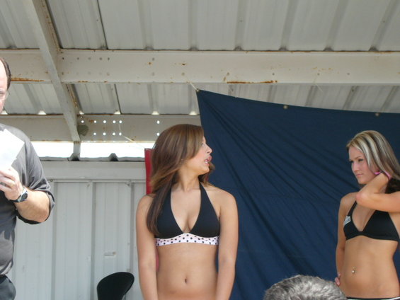 Man holding paper, two women in bikinis on stage