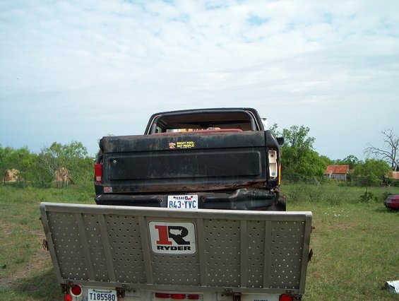 Rear view of a black Ford pickup truck with a trailer attached. Truck has a sticker that says "SHOOT POOL, NOT PEOPLE."