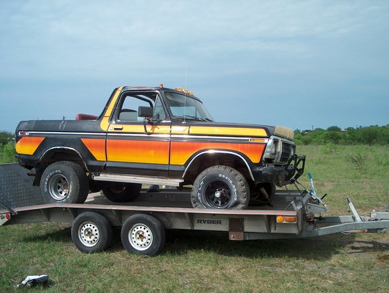 Black and orange 1978 Ford Bronco on a trailer, front bumper damaged