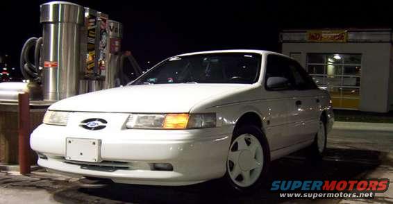 White sedan parked at a gas station at night