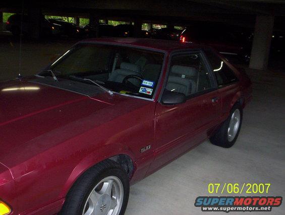 Red 1993 Ford Mustang coupe parked indoors, 3/4 front view, showing side and hood
