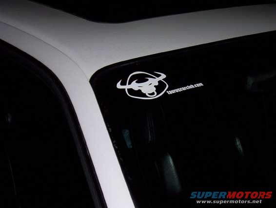 Car interior showing a sticker on the windshield with a bull logo and 'tauruscarclub.com'