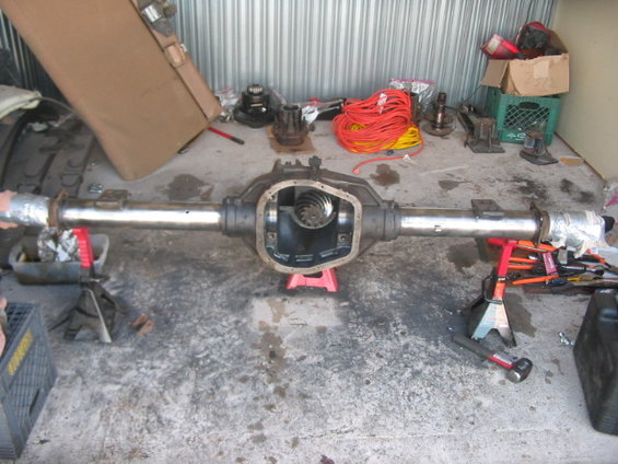 Rear axle assembly on jack stands, differential open, with tools and supplies in background