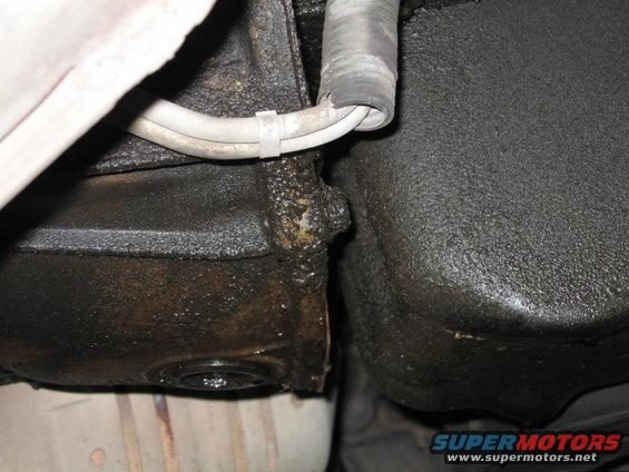 Underside of vehicle showing oil leaks from engine components