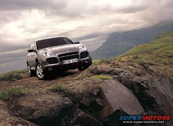 Porsche Cayenne SUV parked on a rocky incline with mountains in the background