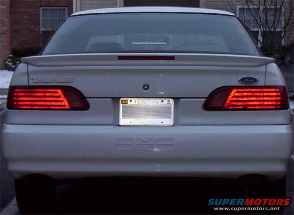 White 1992 Ford Taurus sedan, rear view. Taillights illuminated. Indiana license plate