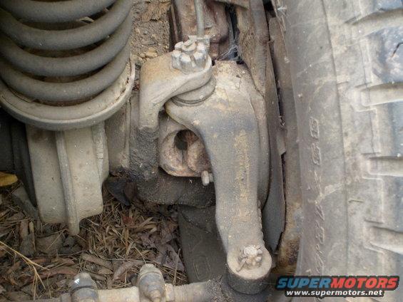 Close-up of a truck's front suspension, showing the coil spring, control arm, and ball joint