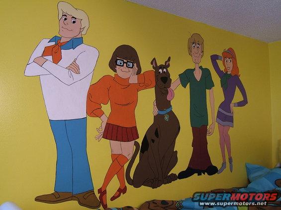 Scooby-Doo gang painted on a yellow wall, with a Supermotors logo at the bottom