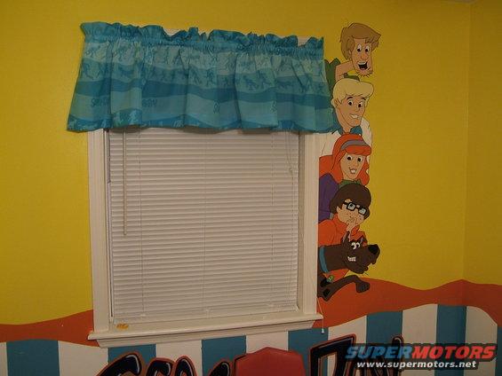 Scooby-Doo characters mural on yellow wall above window with blue valance