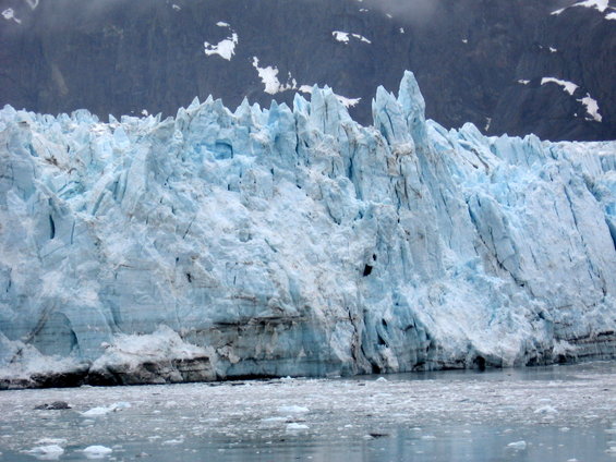 Jagged blue ice glacier face with dark mountains in background