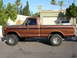 1977 Ford F-150 - A brown 1977 Ford F-150 pickup truck is parked on a street with a house in the background.