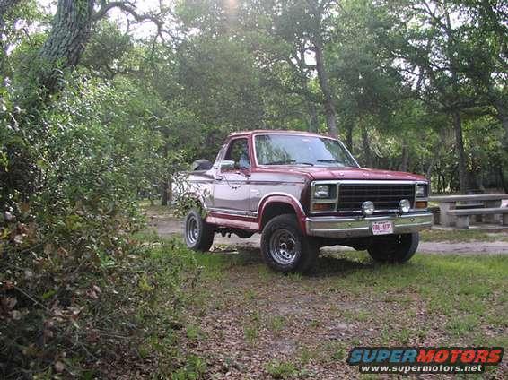 Red and silver 1981 Ford Bronco parked in a wooded area