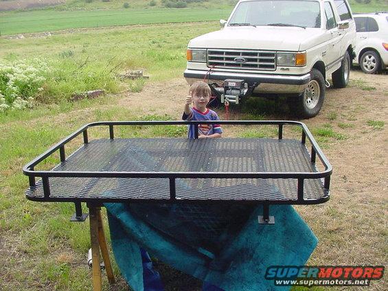 dsc00036.jpg This is the basket I had made for the Bronco.  The nuts are welded into the 1" tubing and will be secured through the Bronco Roof from the inside.  Rubber and silicon will hopefully weatherproof it.  The little guy is my helper.  :)