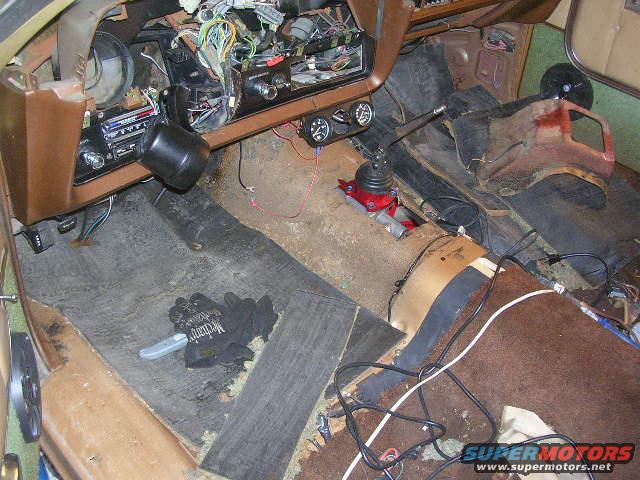 Vehicle interior with exposed wiring, manual shifter, and worn carpeting