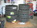 1992 Ford Mustang - Several large off-road tires are stacked in a garage next to a red tool chest and an engine part.