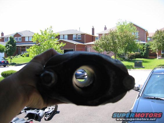 Exhaust pipe part held up to view a blue car through its opening
