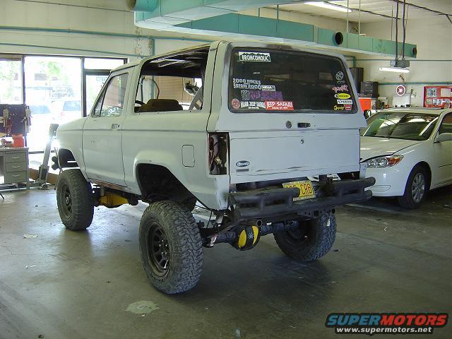 Rear view of a 1986 Ford Bronco II with off-road tires and aftermarket bumper, in a garage