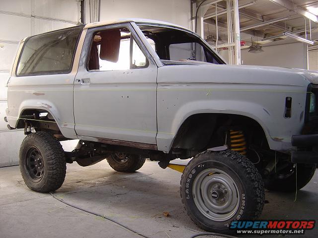 Ford Bronco II body in primer, lifted with aftermarket suspension, in a workshop