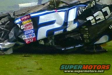 Wrecked race car with blue and white number 21, various sponsor decals
