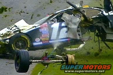 Damaged race car with number 16, detached front axle, on grassy track