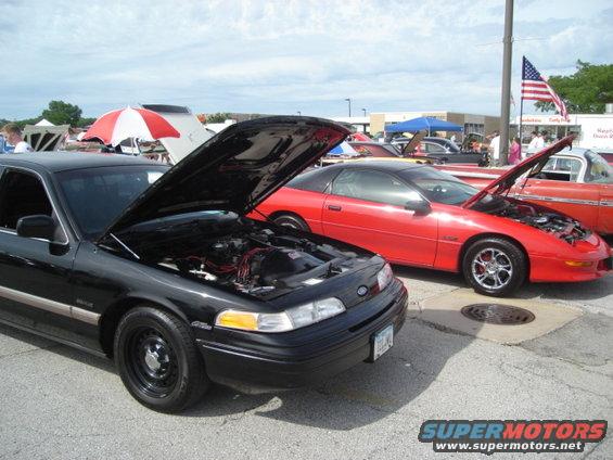 Black 1992 Ford Crown Victoria, front 3/4 view, hood open, parked at car show