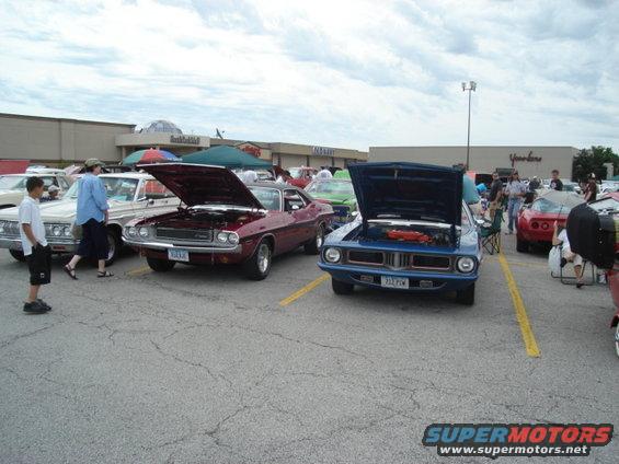 Several classic cars parked at a car show, some with hoods open
