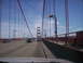 1989 Ford Bronco - Driving across the Golden Gate Bridge, with traffic visible on the roadway and pedestrians on the walkway.
