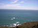 1989 Ford Bronco - A wide view of the ocean and a coastline with sparse vegetation and scattered rocks.