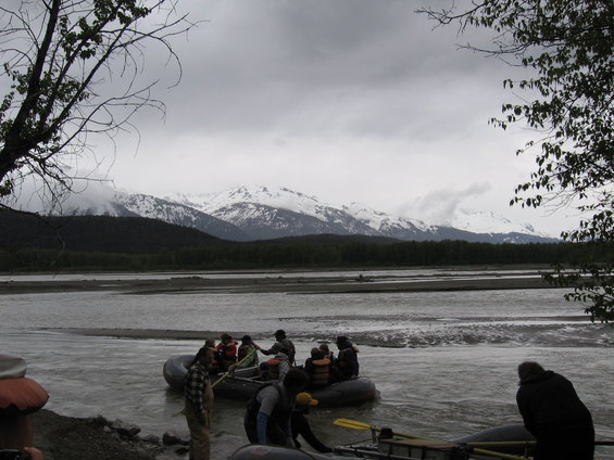 Rafting group on a river with snow-capped mountains in the background