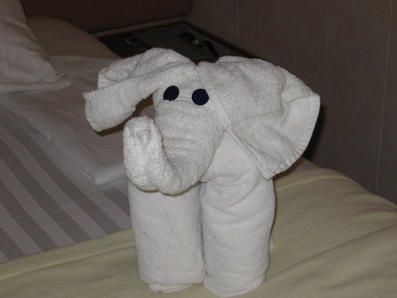 White towel elephant with dark blue eyes on a bed