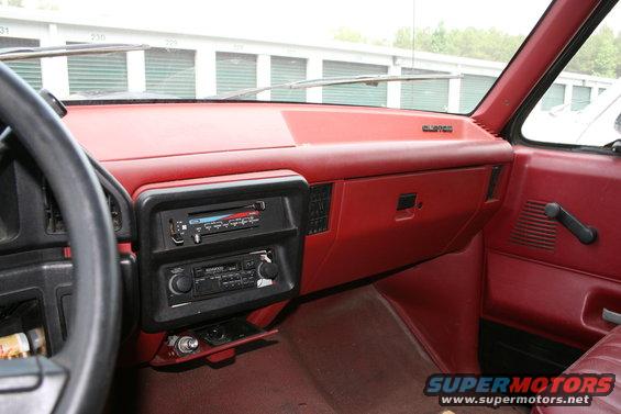Interior view of a pickup truck dashboard with red trim, two radios, and a steering wheel. 'CLIPPER' badge visible on dash