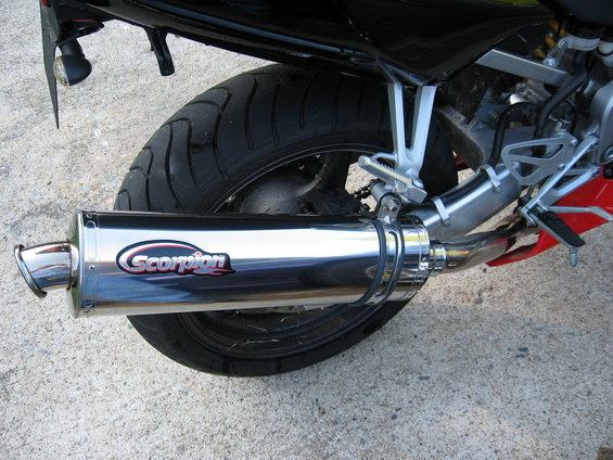 Close-up of a chrome Scorpion exhaust pipe on a motorcycle, with the rear tire visible