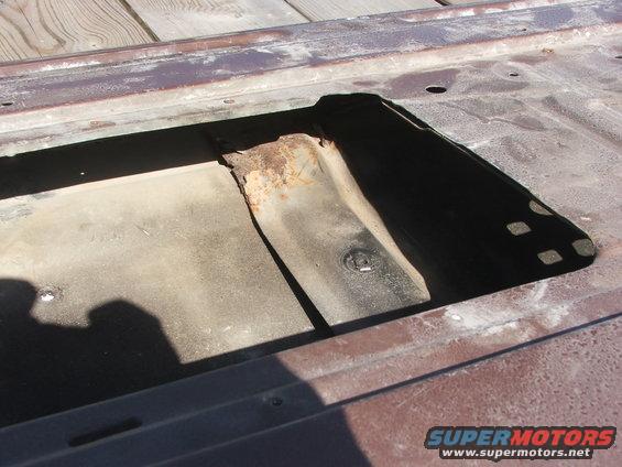 rusted metal panel with rectangular cutout showing internal bracing and some surface rust