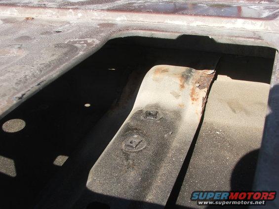 Close-up of a rusted metal bracket inside a vehicle, showing wear and tear