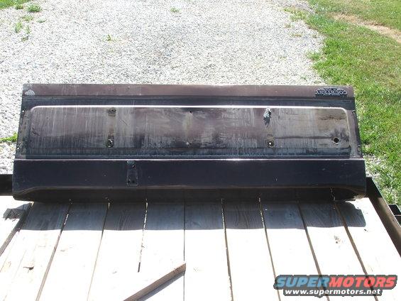 Tailgate with 'COUNTRY' badge on it, sitting on wooden planks