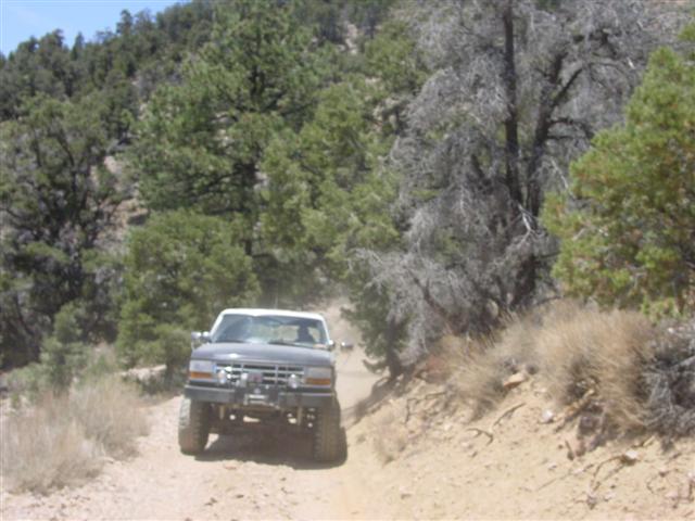 Gray Ford Bronco with winch on front bumper, driving on dirt road