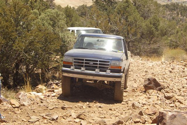 Front view of a blue 1987 Ford F-150 pickup truck on a rocky trail