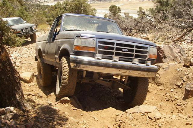 Dark blue Ford Bronco navigating a rocky, off-road trail