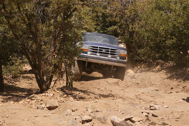 Blue Ford Bronco navigating a rocky, off-road trail