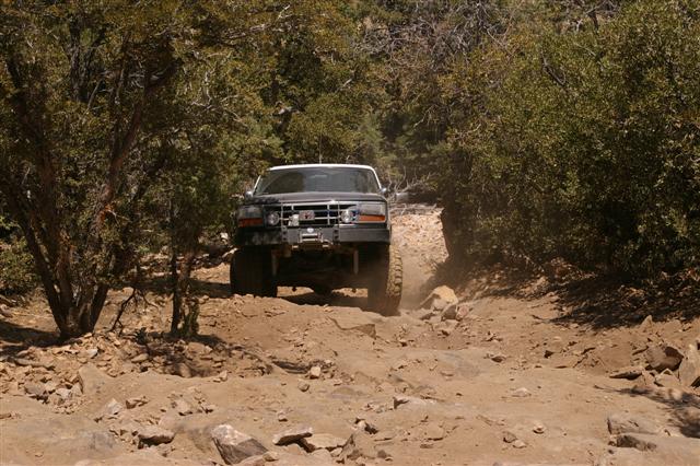 Black Ford Bronco with a winch on the front bumper driving on a rocky, dirt trail