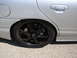 1992 Ford Taurus - Close-up of a silver sedan's rear wheel black aftermarket rims and a lowered stance.