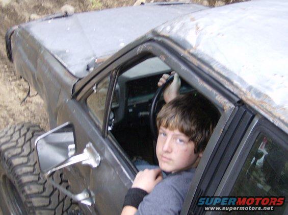 Kid in driver's seat of beat-up off-road vehicle with large tires