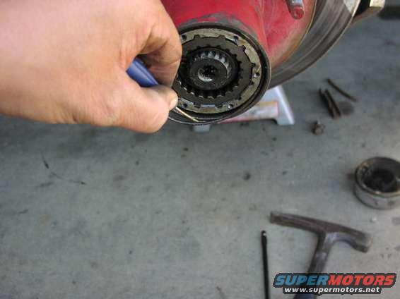 Hand with tool disassembling a vehicle hub assembly with visible splines