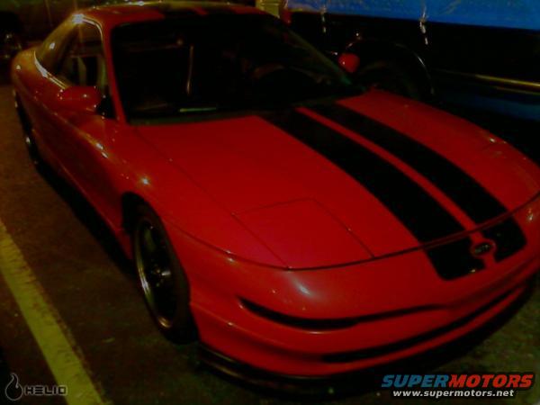 Red 1993 Ford Probe with black racing stripes, front 3/4 view, showing damage on the front bumper