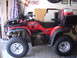 1999 Honda RANCHER - Red Honda Foreman ES ATV parked in a garage, equipped with a cooler and storage boxes on the rear rack.