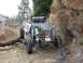 1996 Ford Bronco - An off-road buggy maneuvers through a rocky, mountainous trail with a driver visible from behind.